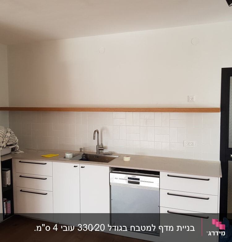 מטבח עם ארונות לבנים ומשטח עבודה מעץ